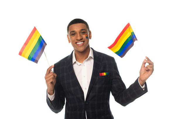 african american transgender woman holding lgbt flags while smiling at camera isolated on white - Фото, изображение
