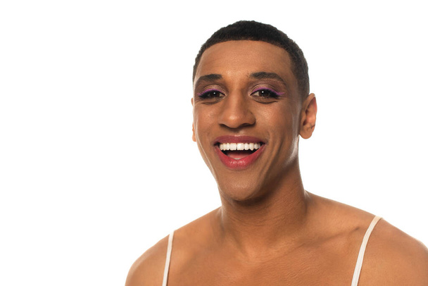 alegre africano americano transexual hombre con maquillaje sonriendo a cámara aislado en blanco - Foto, imagen