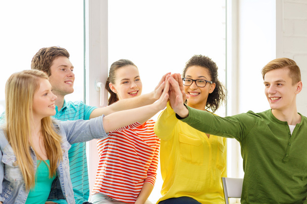 usmívající se studenti vysoké pět gesto sedí - Fotografie, Obrázek
