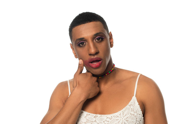 Αφροαμερικάνος τρανσέξουαλ άντρας με μέικ απ και μουτζουρωμένο κραγιόν κοιτάζοντας την κάμερα που είναι απομονωμένη στα λευκά - Φωτογραφία, εικόνα