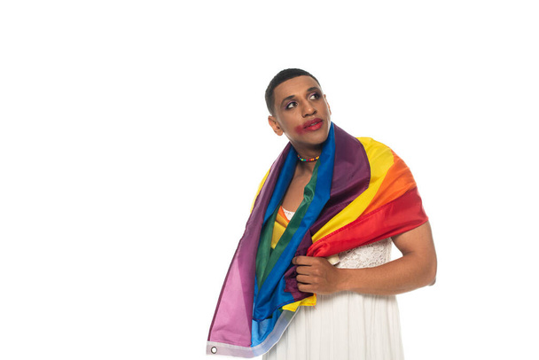 Afrikaans-Amerikaanse transgender man, gewikkeld in lgbt vlag, wegkijkend geïsoleerd op wit - Foto, afbeelding