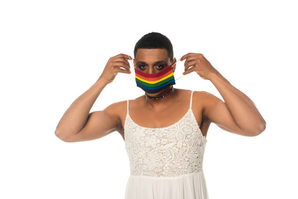 Afričan americký transsexuál muž uvedení na lgbt barvy lékařské masky izolované na bílém - Fotografie, Obrázek