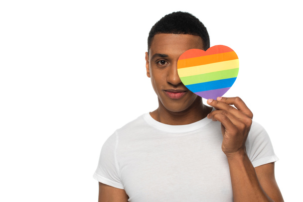 african american man obscuring face with lgbt colors paper heart isolated on white - Foto, Imagem