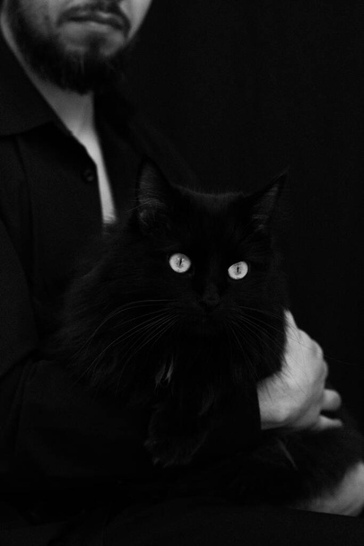 μαύρη γάτα στην αγκαλιά ενός άντρα - Φωτογραφία, εικόνα