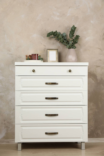 Modern chest of drawers with decor near beige wall - Фото, изображение