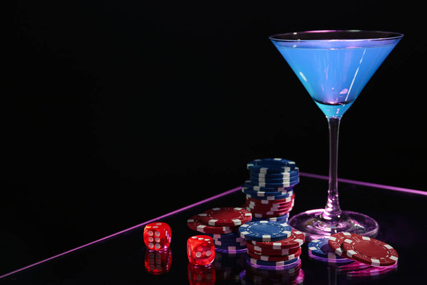 Casino chips, dice and cocktail on dark background, space for text - Foto, Imagen