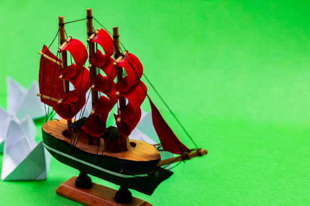 Un giocattolo barca a vela con barche di carta bianca girato da alto punto di vista angolare su sfondo verde - Foto, immagini