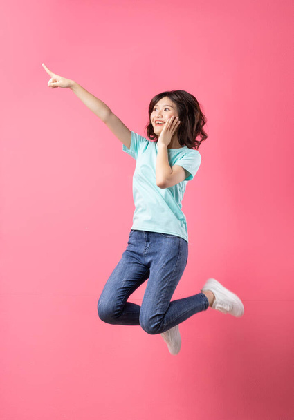Cheerful young girl jumping up on the background - Foto, imagen
