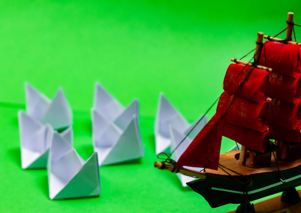 赤い帆と緑の背景に白い紙のボートとおもちゃの船のショットを閉じる高い角度 - 写真・画像