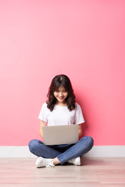 若いアジアの女性がラップトップを使用して床に座って - 写真・画像