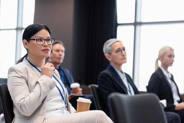 Азиатская деловая женщина с кофе будет сидеть в конференц-зале рядом с коллегами  - Фото, изображение