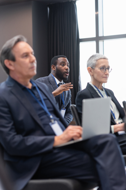Empresário afro-americano conversando perto de colegas turvos na sala de conferências  - Foto, Imagem