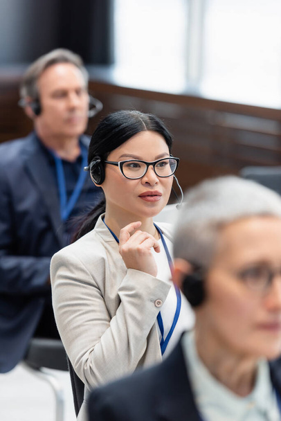 Asian businesswoman in headset sitting in conference room during training  - Φωτογραφία, εικόνα