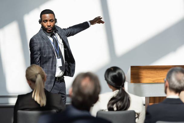 back view of business people near african american lecturer pointing with finger during conference - Photo, Image