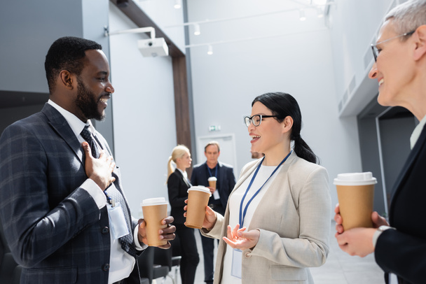 mosolygó többnemzetiségű üzleti kollégák kávé menni beszélni ülés közben - Fotó, kép