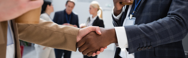 interraciale zakenmannen schudden handen in de buurt van collega 's op wazig achtergrond, banner - Foto, afbeelding