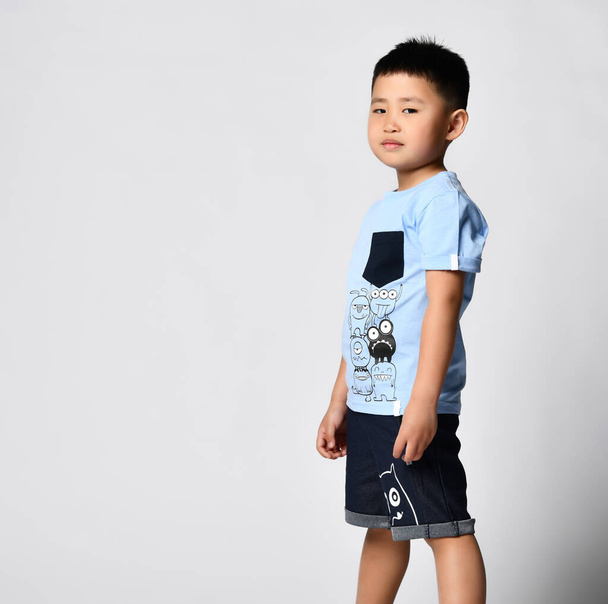 Asiático chico en verano camiseta y pantalones cortos en cuclillas aislado studio shot - Foto, Imagen