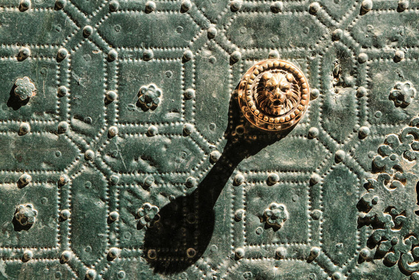Красивая и винтажная дверная ручка льва в форме зеленой металлической двери с отделкой украшений и баластеров - Фото, изображение