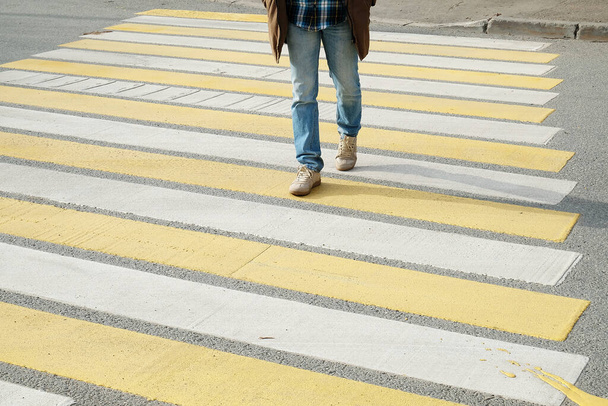 Hombre cruzando la calle en un cruce peatonal de rayas blancas y amarillas - Foto, imagen