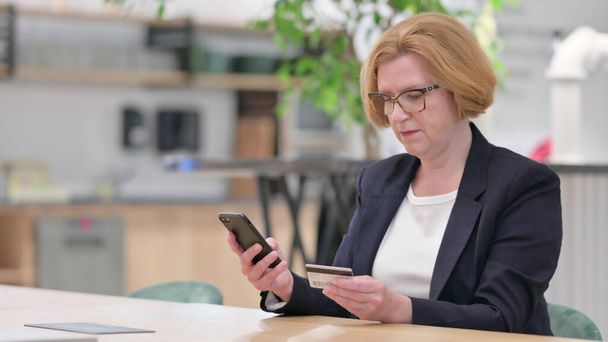Businesswoman Doing Online Payment via Smartphone in Office - Foto, immagini