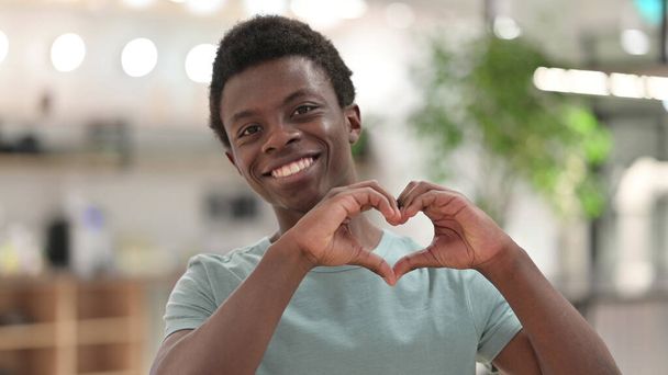 Retrato de un joven africano mostrando un signo cardíaco con la mano - Foto, imagen