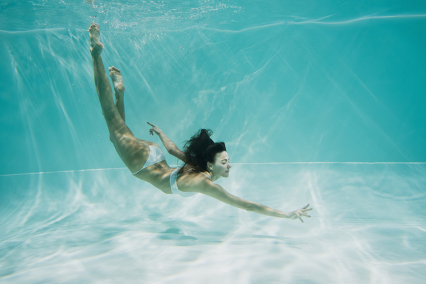 zierliche Frau im weißen Badeanzug taucht in Schwimmbad  - Foto, Bild