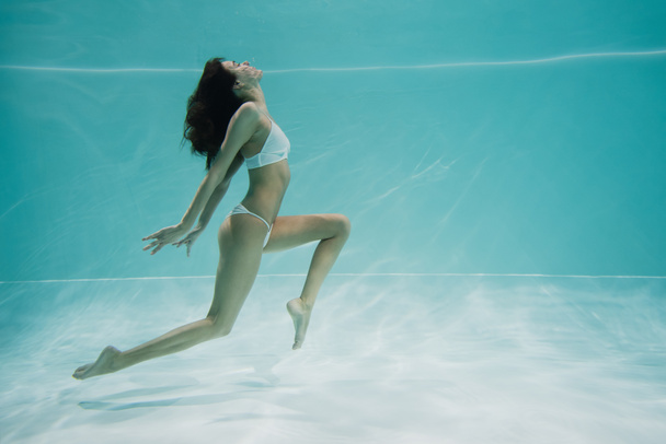 χαριτωμένη γυναίκα με μαγιό που κολυμπάει στην πισίνα  - Φωτογραφία, εικόνα