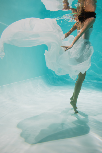 cropped view of young woman in white dress swimming in pool  - Fotoğraf, Görsel