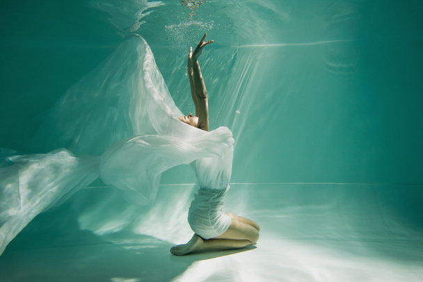 Nuori nainen mekko istuu uima-altaassa sininen vesi  - Valokuva, kuva