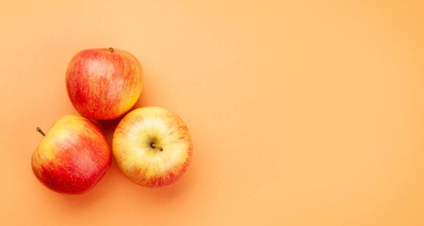 Fresh ripe red apple fruits on peach background. Top view flat lay with copy space - Fotoğraf, Görsel