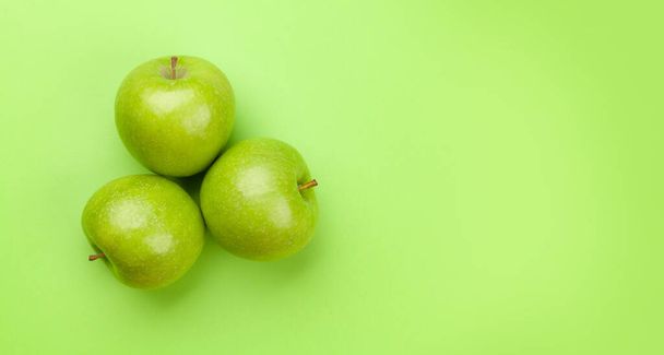 Fresh ripe green apple fruits on green background. Top view flat lay with copy space - Photo, image