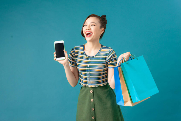 幸せな若い魅力的な女性がショッピングバッグを持ち携帯電話を持ち - 写真・画像