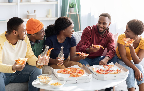 Vreugdevolle Afrikaanse Amerikaanse millennial vrienden eten pizza - Foto, afbeelding