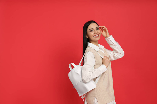 Young woman with stylish backpack on red background. Space for text - Foto, immagini