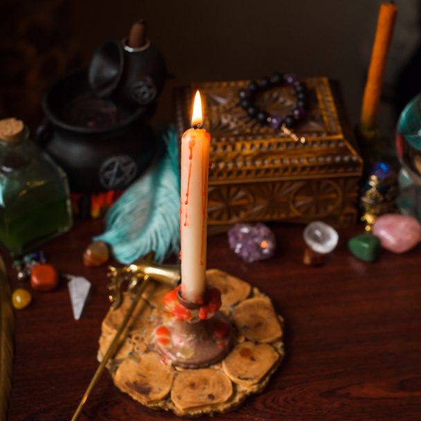 Eine Wahrsagerin, Hexensachen auf einem Tisch, Kerzen und Wahrsagerobjekte. Das Konzept der Wahrsagerei, Astrologie und Esoterik - Foto, Bild