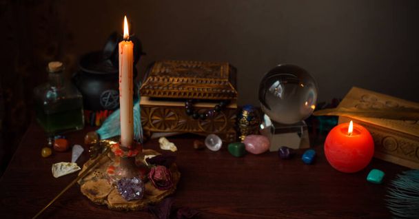 Une diseuse de bonne aventure, des trucs de sorcière sur une table, des bougies et des objets de voyance. Le concept de divination, astrologie et ésotérisme - Photo, image