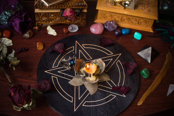 Een waarzegster, heksenspullen op een tafel, kaarsen en waarzeggerij. Het concept van waarzeggerij, astrologie en esoterie - Foto, afbeelding