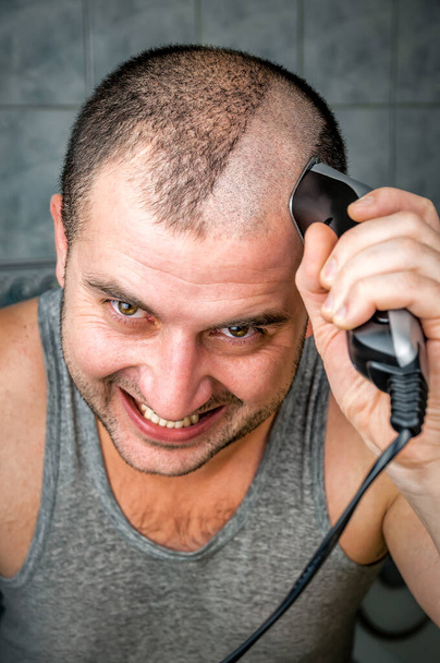 crazy man cuts himself by hair clipper - Foto, afbeelding