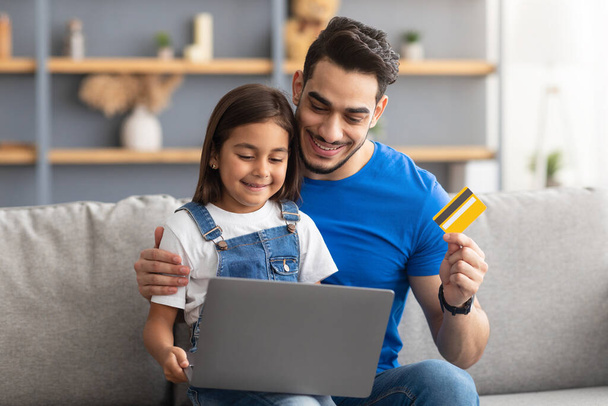 Famille utilisant l'ordinateur et la carte de crédit à la maison - Photo, image