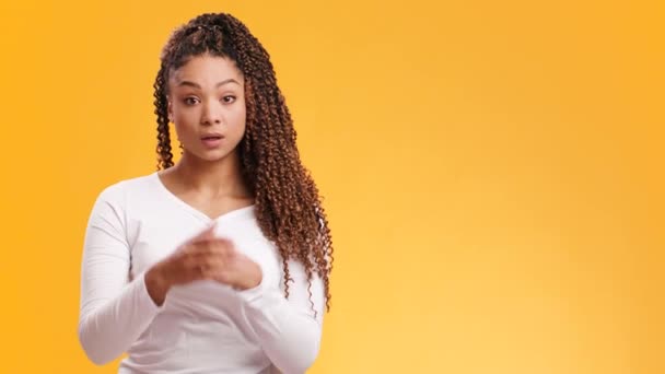 Joven mujer afroamericana sintiéndose conmocionada, cubriéndose la boca con asombro, fondo de estudio naranja con espacio vacío - Metraje, vídeo