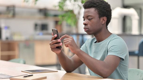 Νεαρός Αφρικανός που χρησιμοποιεί Smartphone, Περιήγηση στο Internet - Φωτογραφία, εικόνα