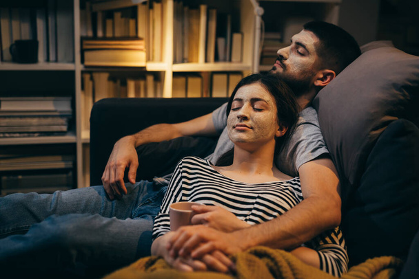 couple relaxing at home with cosmetic face mask applied on faces - Foto, immagini