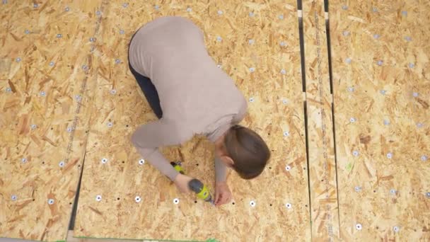 TOP DOWN: Woman fastens metal washers onto a plywood board with a power drill. - Footage, Video
