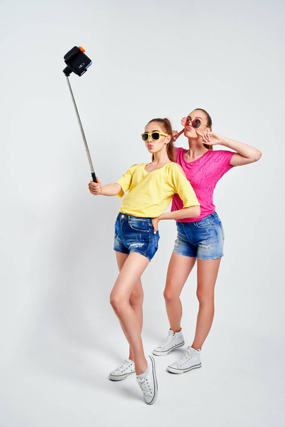 portrait of happy teenagers taking selfie together isolated on whitePortrait of happy teenagers in summer clothes, sunglasses taking selfie together isolated on white. - Foto, imagen