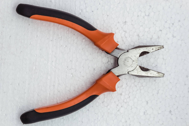Pliers tool with a plastic handle lie on a white background, top view. - Fotó, kép