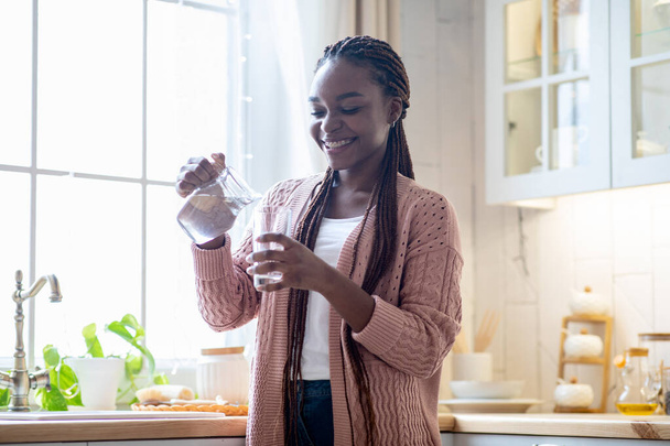 Healthy Drink. Happy Young African American Female Drinking Water In Kitchen - 写真・画像