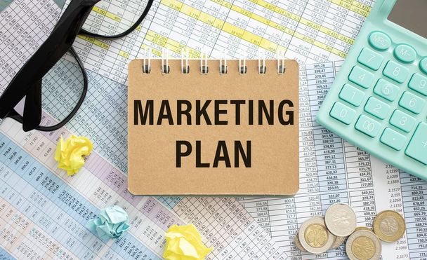 Marketing plan written on notepad, office desk with calculations and calculator, concept image for blog title or header image. - Foto, Imagen