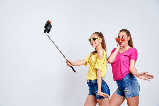 portrait of happy teenagers taking selfie together isolated on whitePortrait of happy teenagers in summer clothes, sunglasses taking selfie together isolated on white. - Fotó, kép