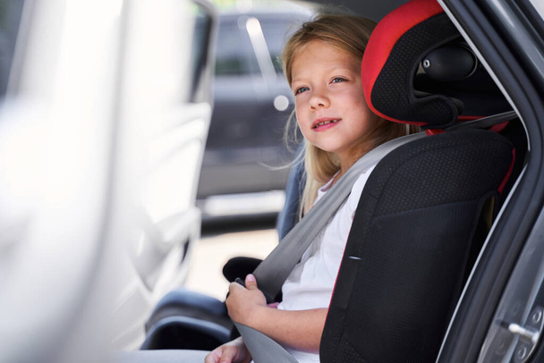 Smiling girl sitting in child car sit - Photo, image