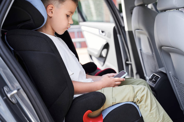 Cute boy playing mobile games in car - Photo, image